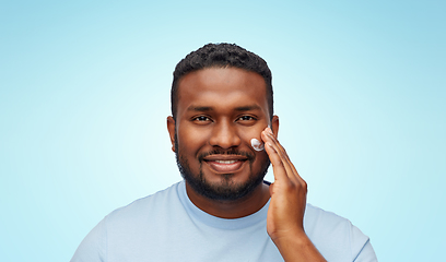 Image showing african american man applying moisturizer to face