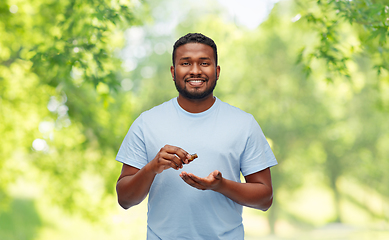 Image showing smiling african man applying grooming oil to beard