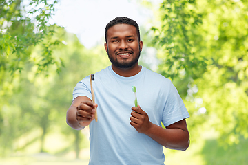 Image showing african man with wooden and plastic toothbrushes