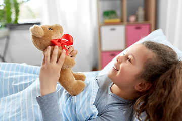 Image showing happy little girl with teddy bear lying in bed