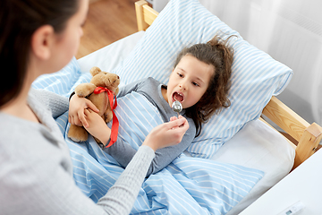 Image showing mother giving cough syrup to sick daughter