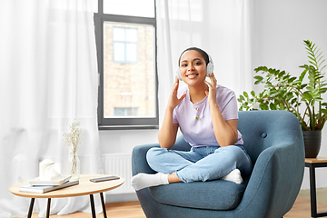 Image showing woman in headphones listening to music at home