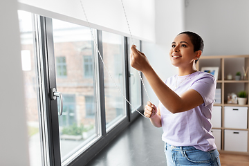 Image showing woman opening window roller blinds