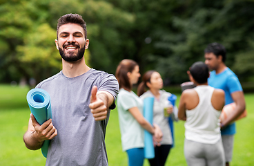 Image showing smiling man with yoga mat showing thumbs up