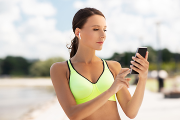 Image showing woman with earphones and smartphone doing sports
