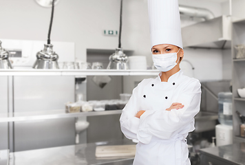 Image showing female chef in mask with crossed arms at kitchen