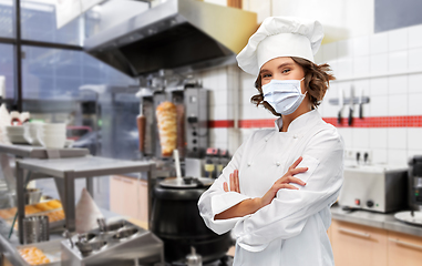 Image showing female chef in mask with crossed arms at kitchen