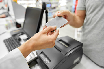 Image showing close up of hand giving bank card to pharmacist