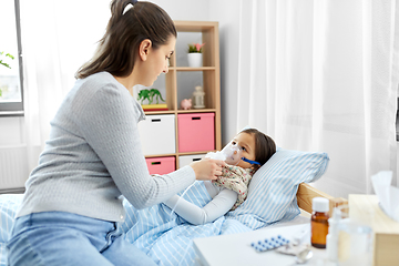 Image showing mother and sick daughter with oxygen mask in bed