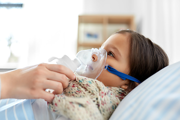 Image showing mother and sick daughter with oxygen mask in bed