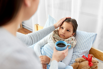 Image showing mother giving tea to sick daughter lying in bed