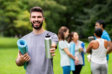 Image showing smiling man with yoga mat over group of people
