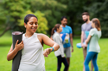 Image showing smiling woman with yoga mat and fitness tracker