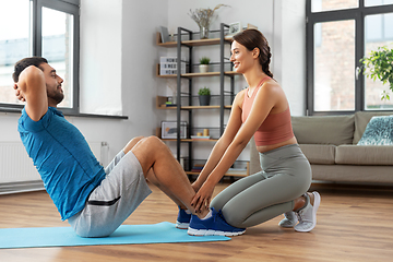 Image showing man with personal trainer doing sit ups at home