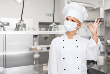 Image showing female chef in mask showing ok sign at kitchen