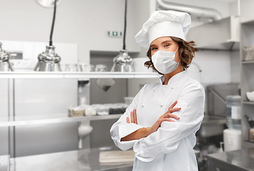 Image showing female chef in mask with crossed arms at kitchen