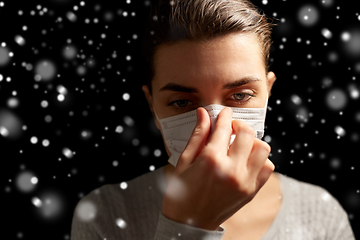 Image showing sick woman adjusting protective medical face mask