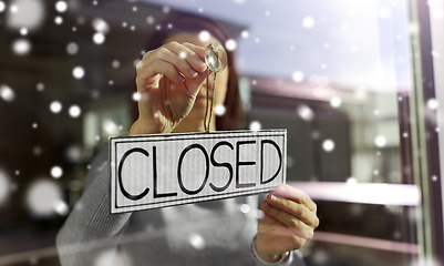 Image showing woman hanging banner with closed word on door