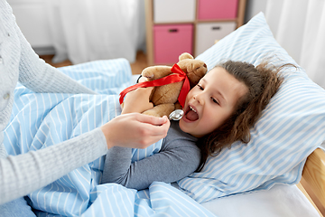 Image showing mother giving cough syrup to sick daughter