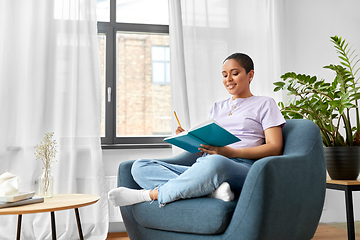 Image showing happy african american woman with diary at home