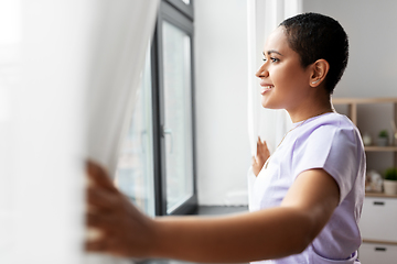 Image showing happy african american woman looking out of window