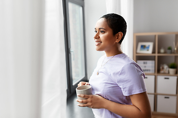 Image showing happy woman with coffee looking out of window