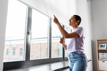 Image showing woman opening window roller blinds