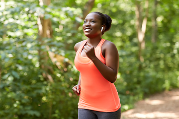 Image showing happy african woman in earphones running in park