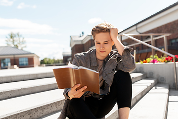 Image showing young man or teenage boy reading book in city