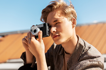 Image showing young man with camera photographing in city