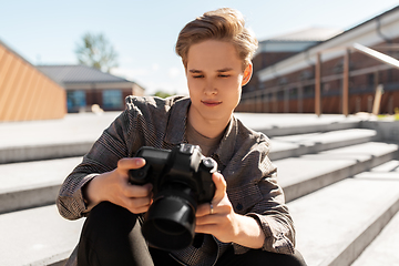 Image showing young man with camera photographing in city