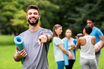 Image showing happy man with yoga mat pointing finger to camera