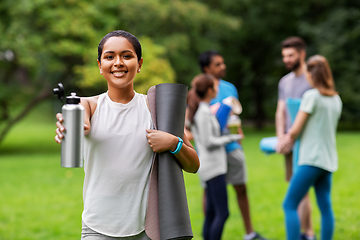 Image showing smiling woman with yoga mat and bottle at park