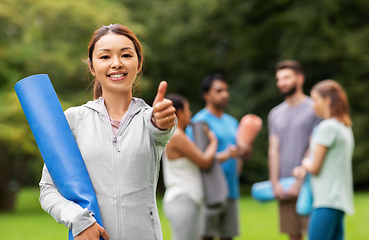 Image showing smiling woman with yoga mat showing thumbs up