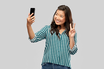 Image showing smiling asian woman taking selfie by smartphone