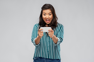 Image showing surprised asian woman using smartphone