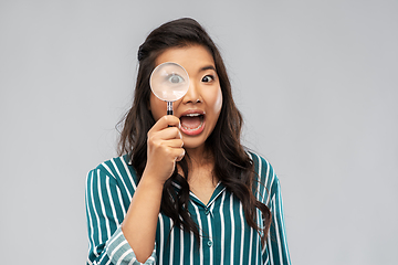 Image showing asian woman looking through magnifying glass