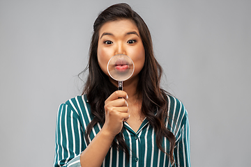 Image showing happy asian woman with magnifying glass on lips