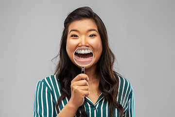 Image showing asian woman shows teeth through magnifying glass