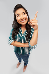 Image showing happy smiling asian woman pointing finger up