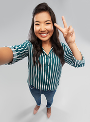 Image showing happy asian woman taking selfie and showing peace