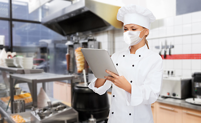 Image showing female chef in mask with tablet pc at kitchen