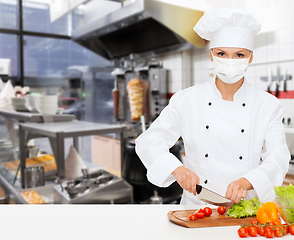 Image showing female chef in mask cutting vegetables at kitchen