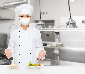 Image showing female chef in mask showing food at kitchen