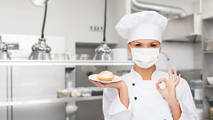 Image showing female chef in mask showing ok sign at kitchen