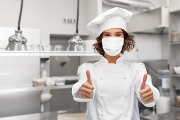 Image showing female chef in mask showing thumbs up at kitchen