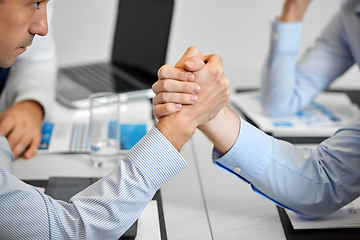 Image showing close up of businesspeople arm wrestling at office