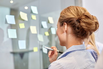 Image showing business team with sticky notes on glass at office