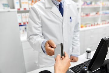 Image showing close up of hand giving bank card to pharmacist