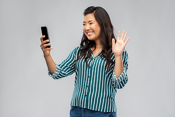 Image showing happy asian woman with smartphone waving hand